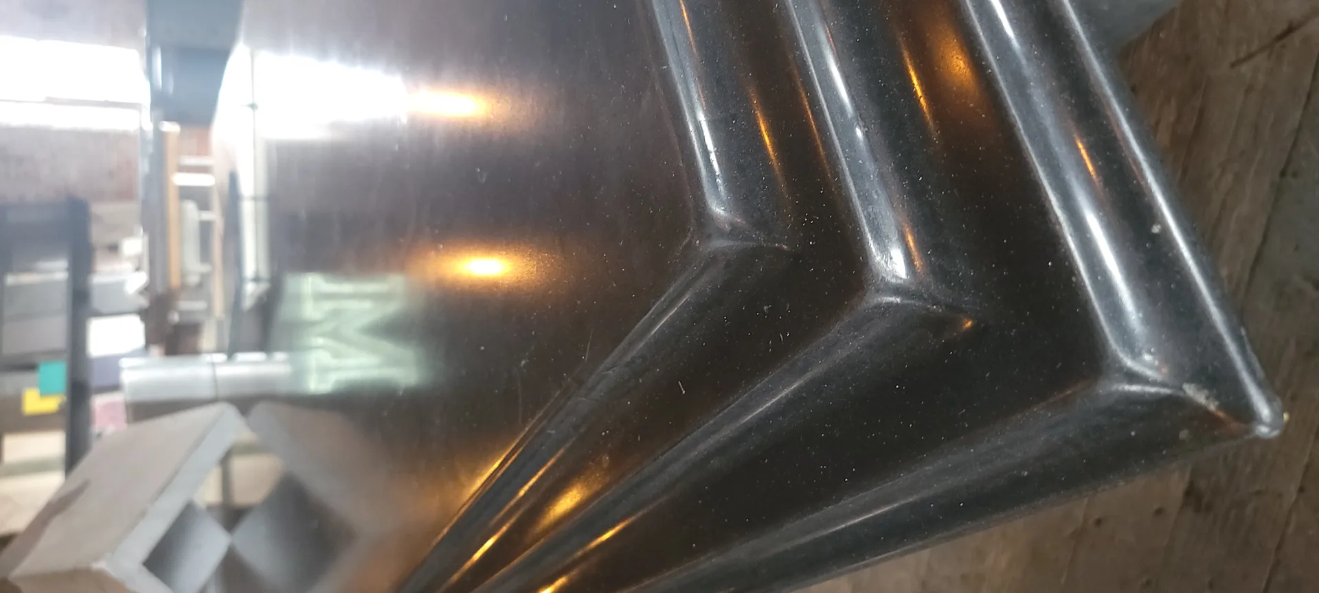 Close-up of black vehicle side mirror with amber turn signal and chrome trim in daylight