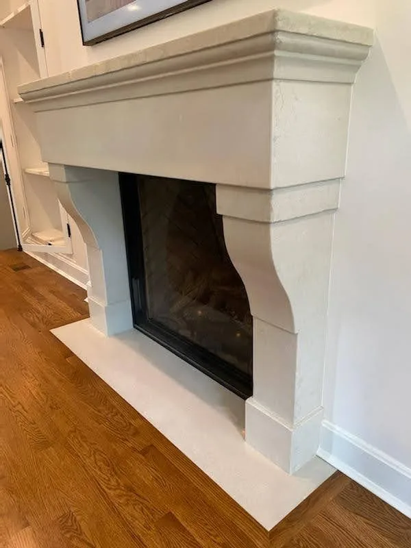 Modern white fireplace with black insert and hearth on wood floor against white walls