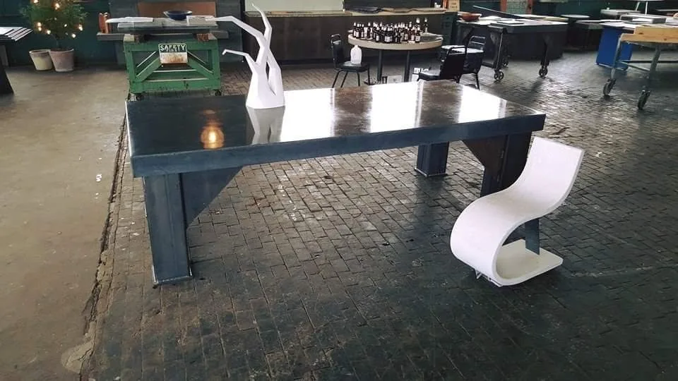 Dark blue table with white sculptural chair in industrial Cincinnati studio