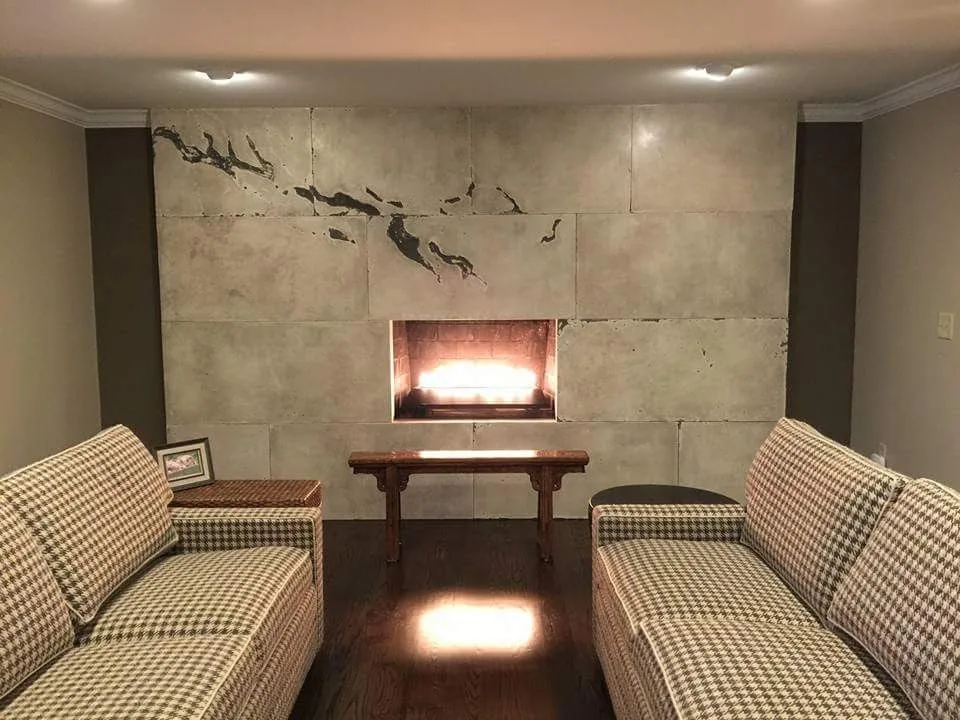 Modern living room with two checkered sofas facing each other, fireplace with glowing insert in tiled wall, wooden table between seating, and dark wood flooring