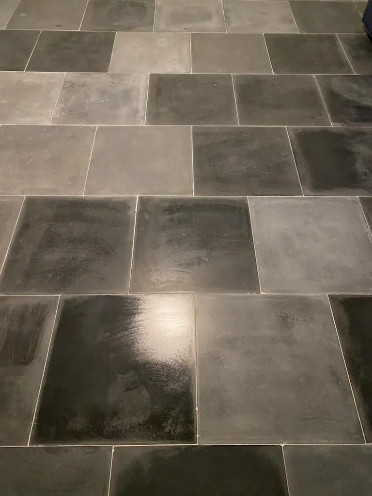 Large format gray tile flooring with varied tones and subtle texture, arranged in a staggered brick pattern with light grout lines