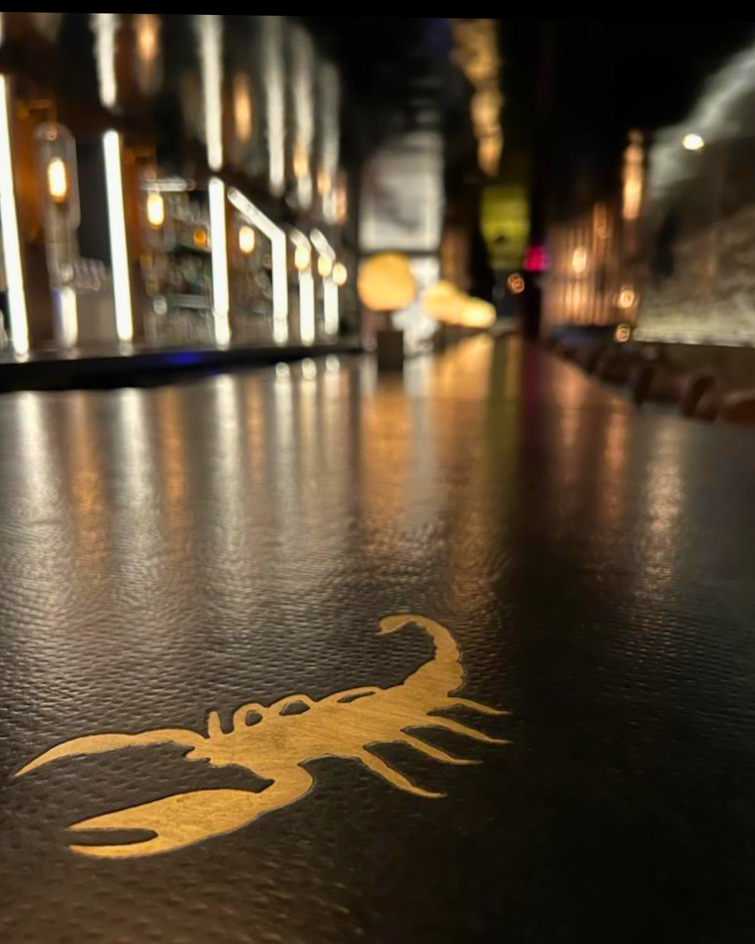 Gold scorpion logo on concrete bar with ambient yellow lighting