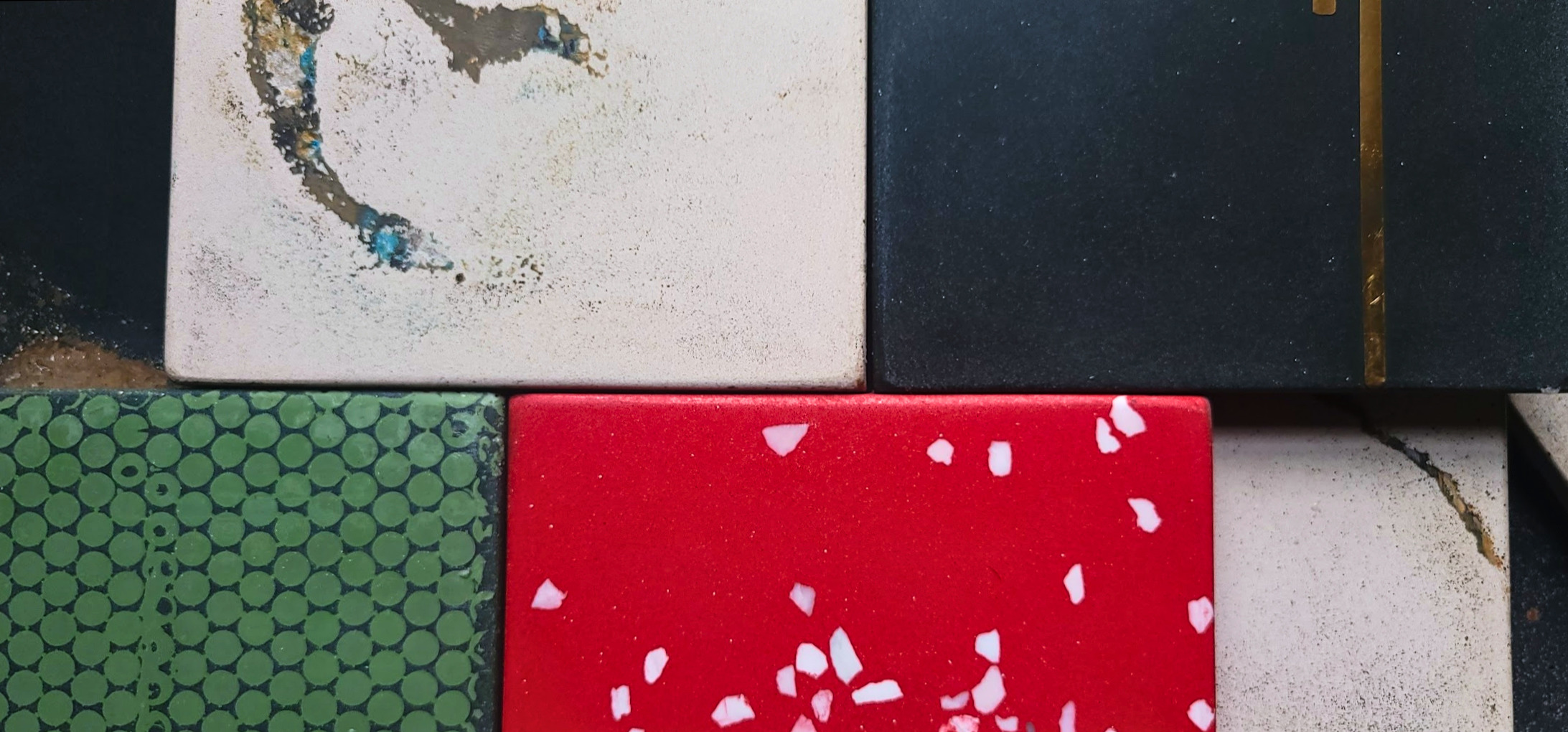 Colorful tile collection featuring red mushroom pattern, green circular design, white speckled, and dark tiles arranged together