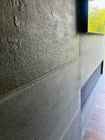 Concrete wall with horizontal seam and wooden floor along Cincinnati building interior with window showing green outdoor view