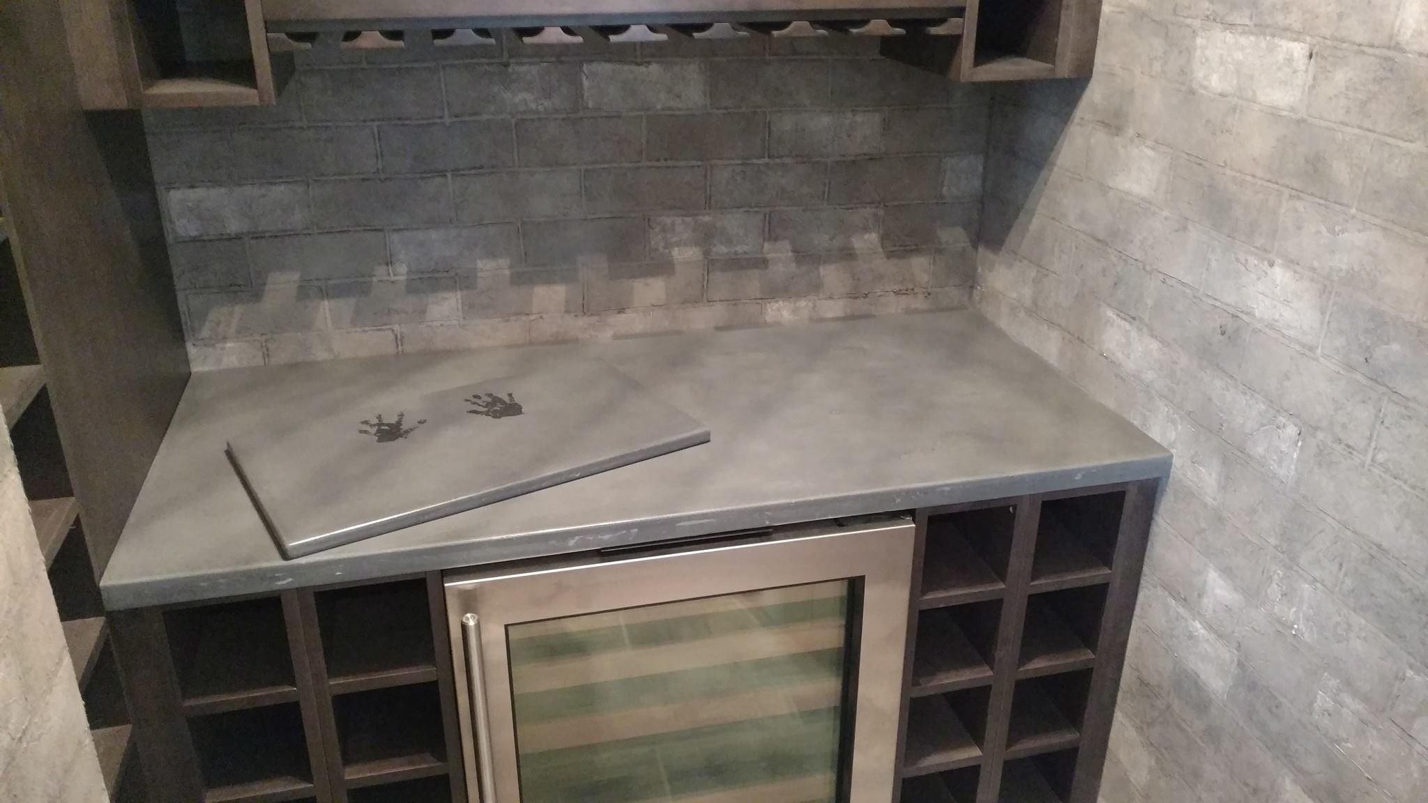 Stainless steel bar top with cooler cabinet and open shelving built into concrete block wall