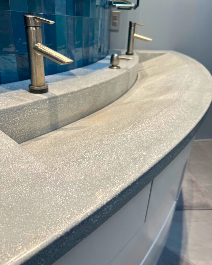 Modern bathroom sink with sparkly gray countertop, sleek chrome faucet, and blue tile backsplash