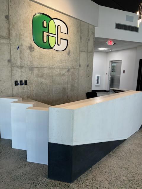 Modern reception desk with green and white GC logo on concrete wall, Cincinnati office interior