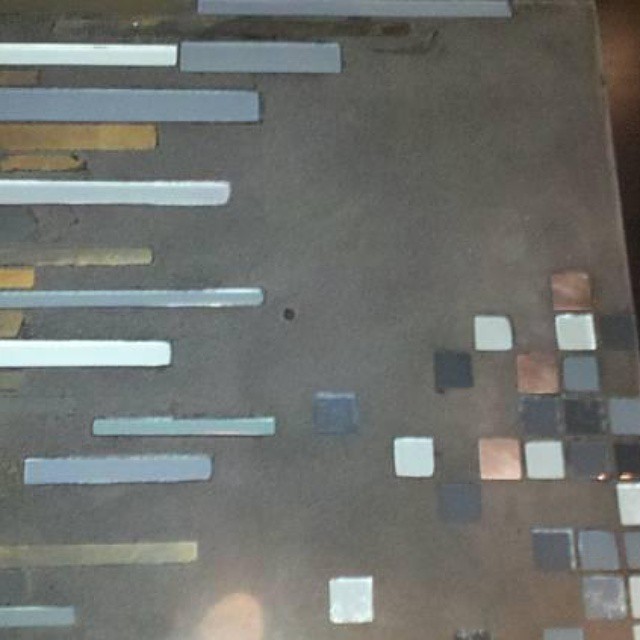 Concrete surface displaying custom color samples and finish options in strips and squares, including whites, grays, tans, and copper tones